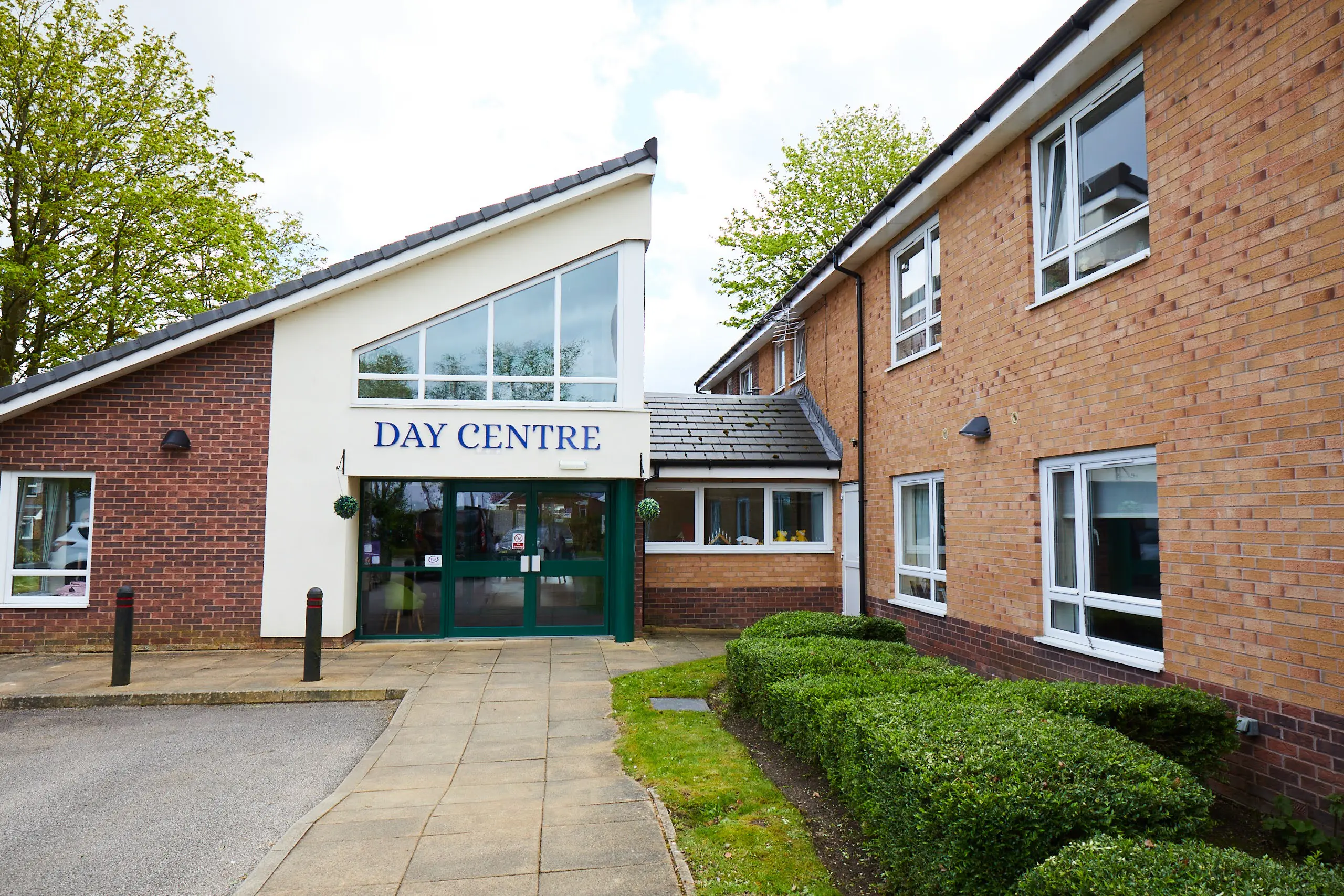 Path leading to building angles roof and Day Centre sign.