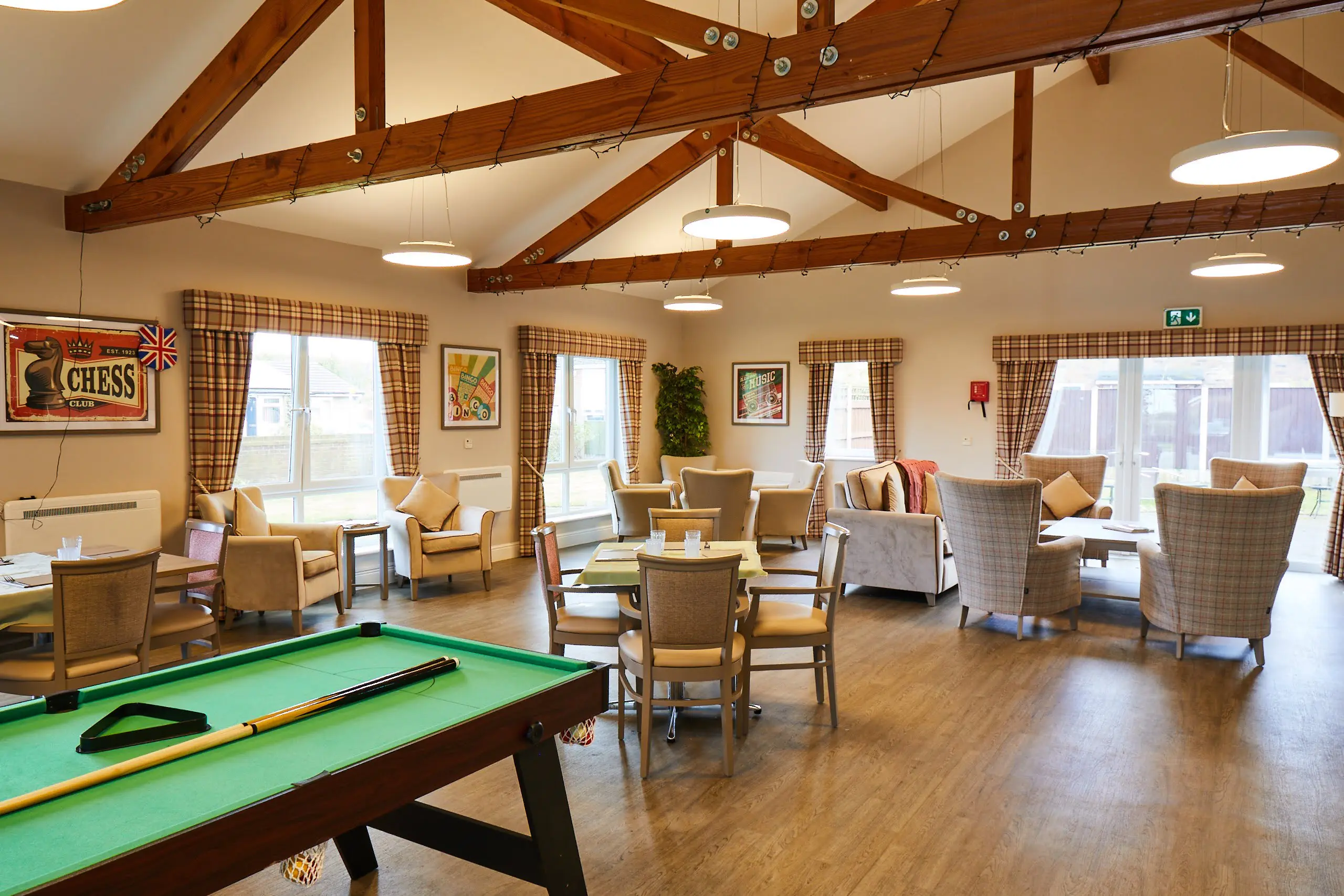 Wide view of Brampton Lodge Day Centre lounge with he pool table, tables and chairs, sofas and arm chairs