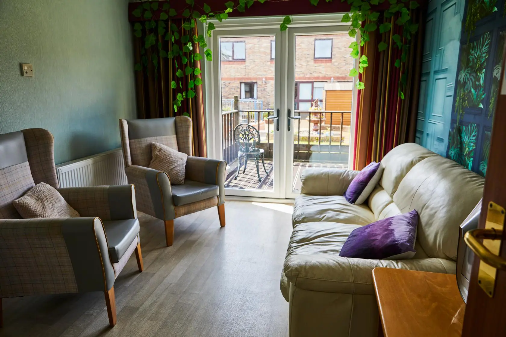 Comfortable sofa and arm chairs with purple throw cushions in a lounge area at Spiers Care Home