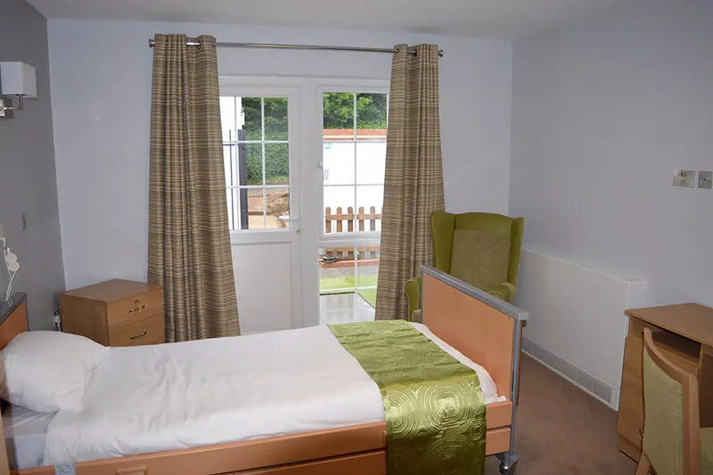 A ground floor bedroom at Berehill with glass door leading to a patio outside.