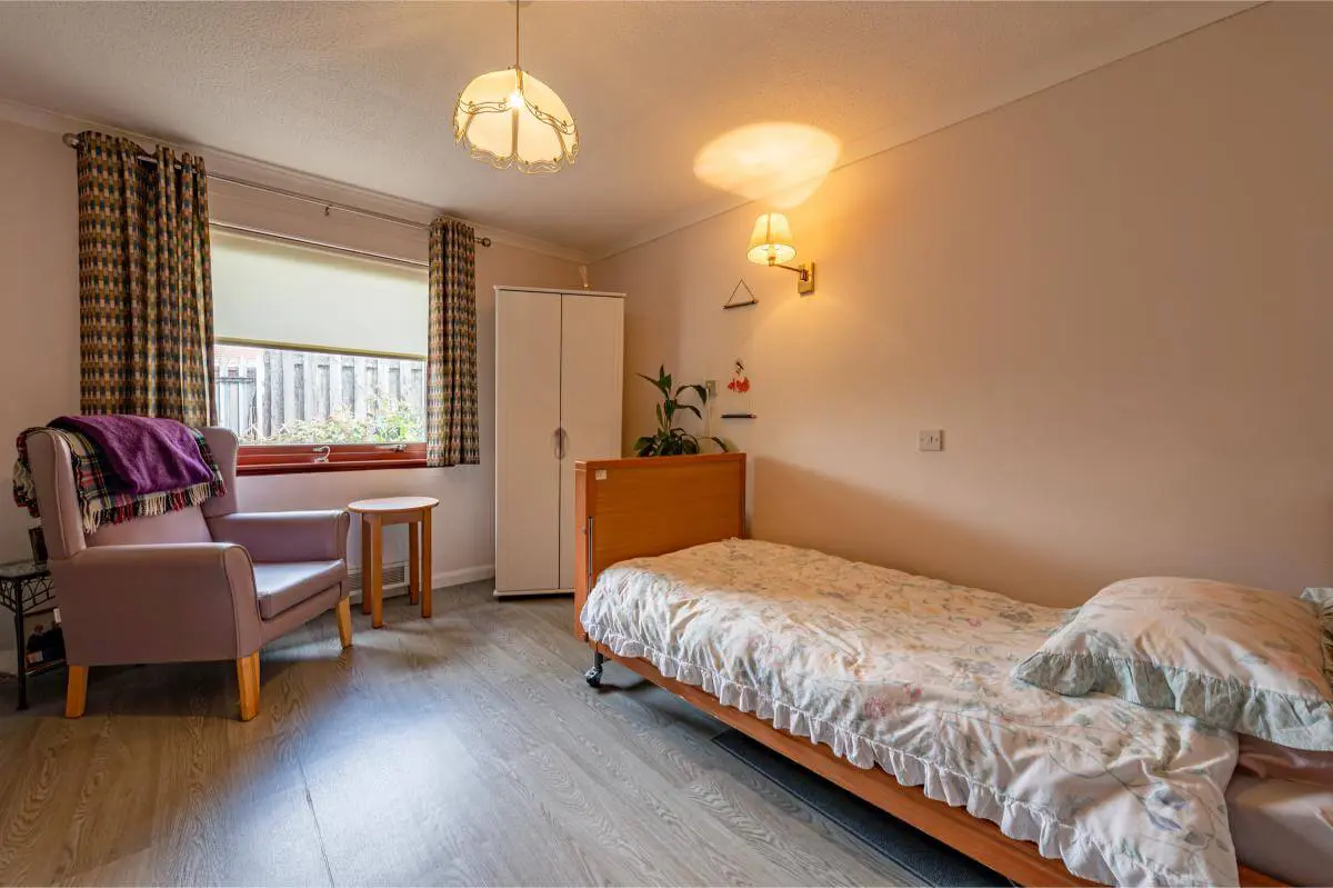 View of the bed, arm chair and wardrobe in a bedroom at Spiers Care Home.