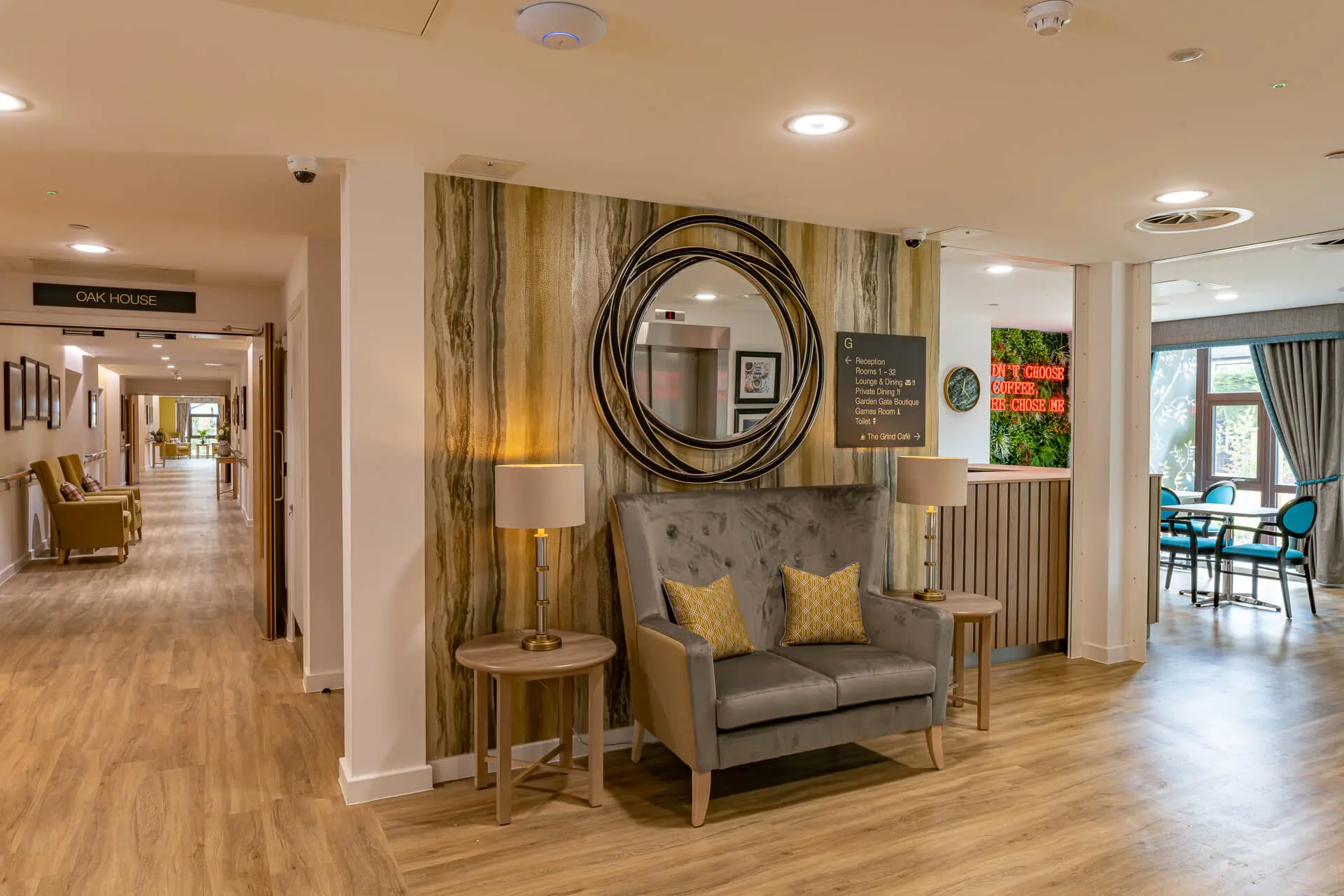 Sofa under mounted, circular wall mirror in the entrance at Surbitonain