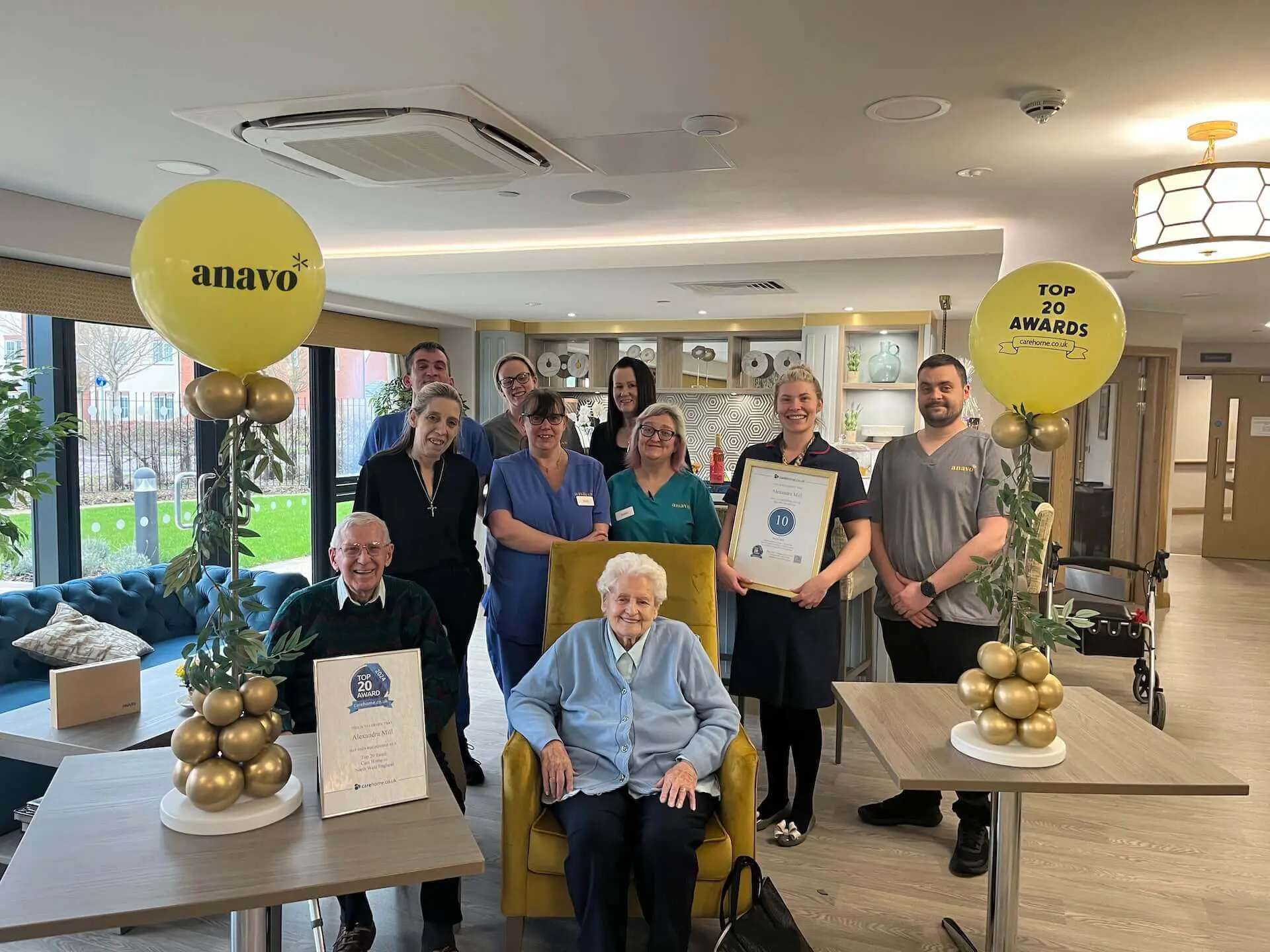 2 residents siting down and eight staff members at Alexandra Mill holding their top 20 care home certificate.