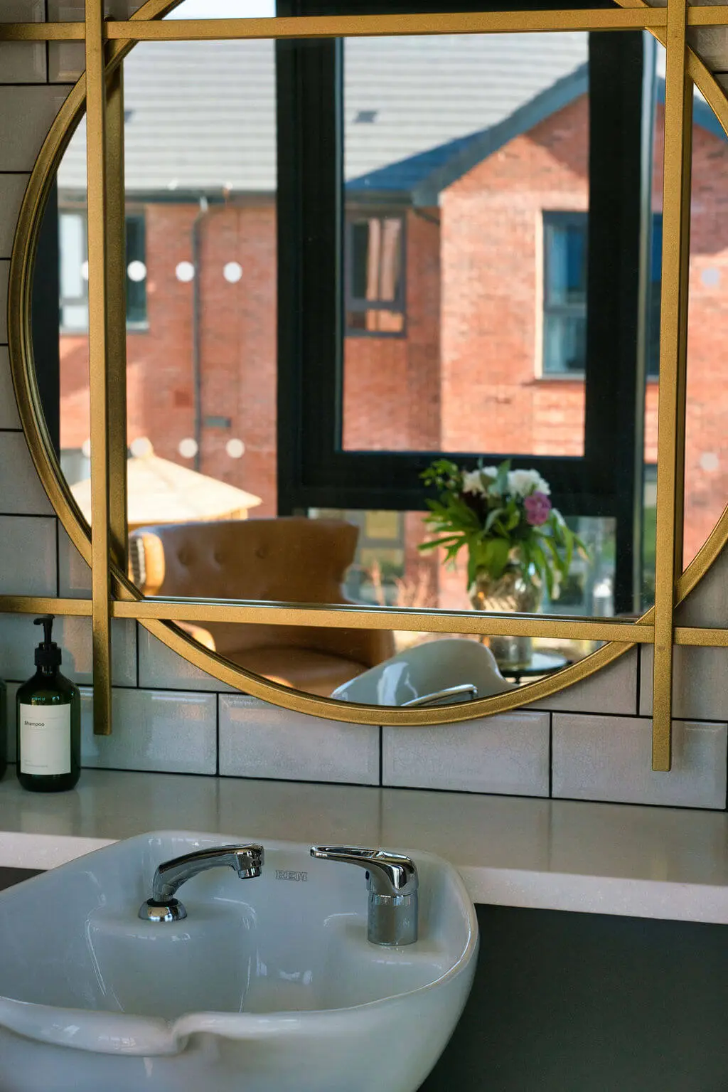 A hair washing basin with a mirror reflecting a building.