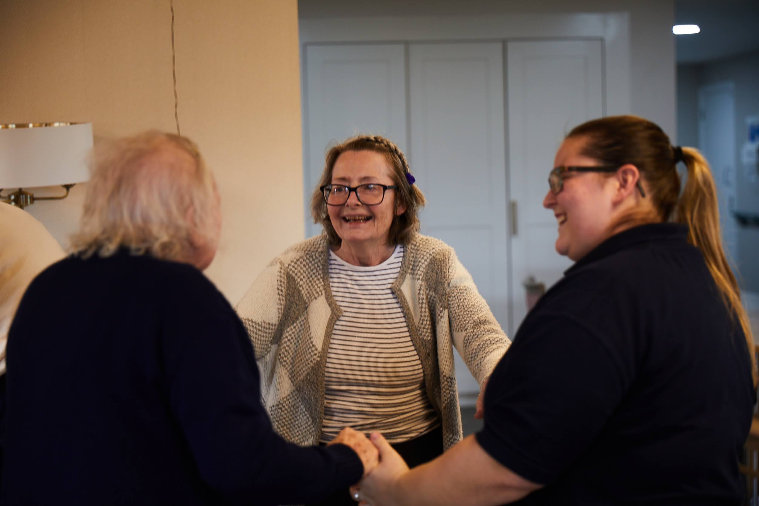 Two Brampton Day Centre guests smiling while dancing with a staff member