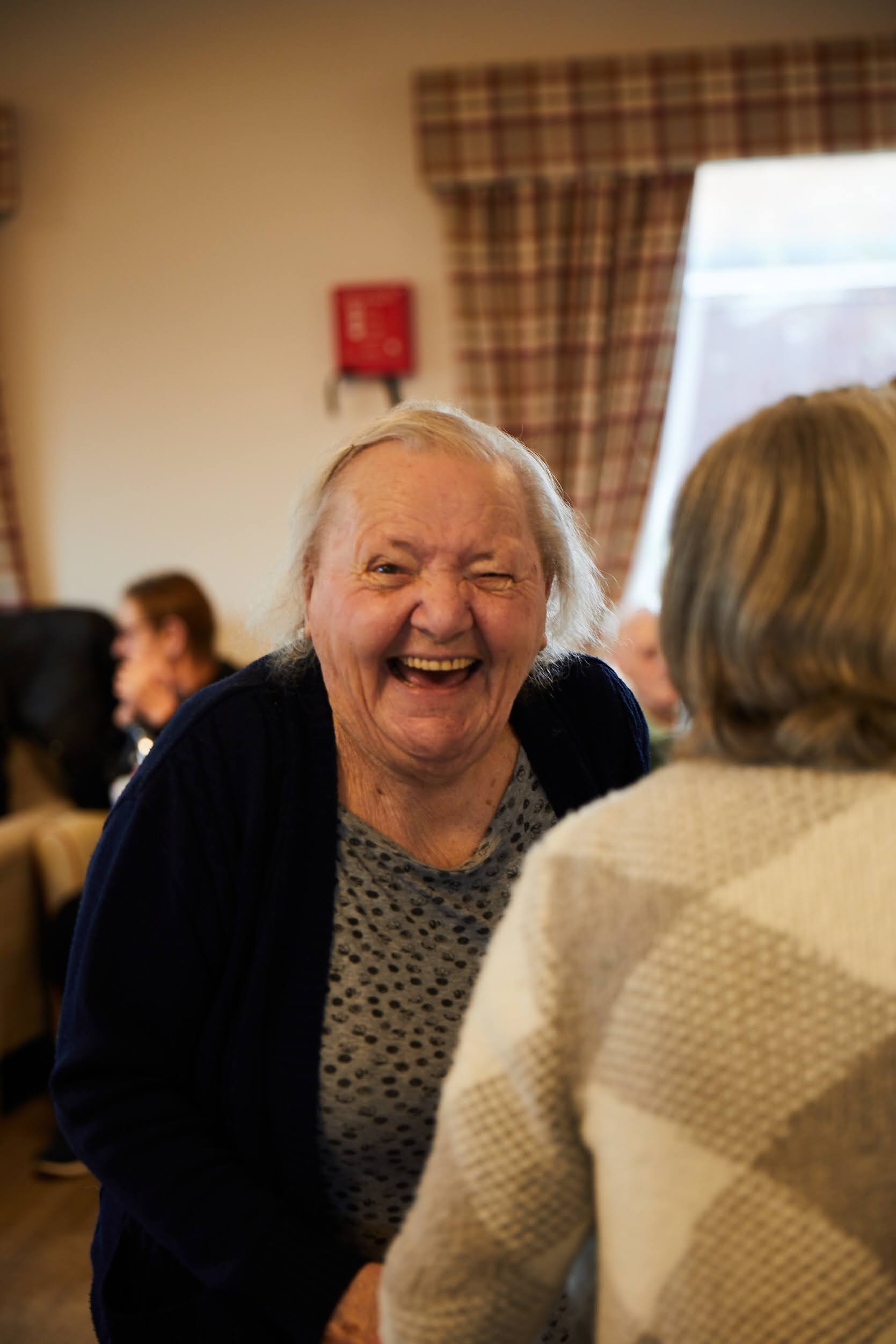 A lady smiling while dancing in the lounge at Brampton Lodge Day Centre