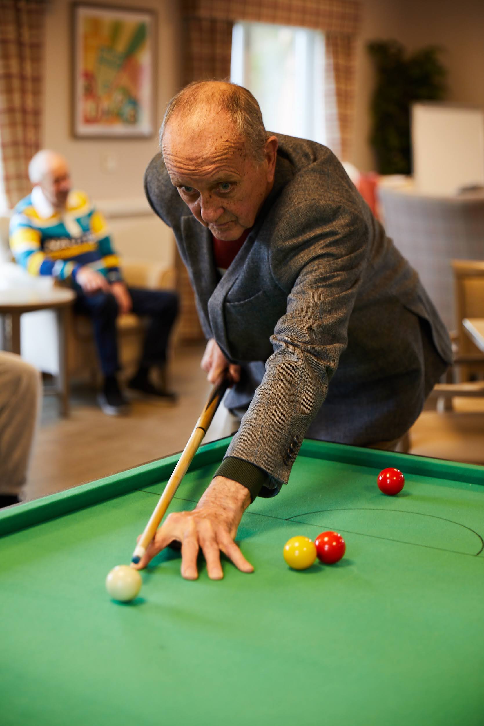 A man playing pool in the lounge at Brampton Lodge Day Centre