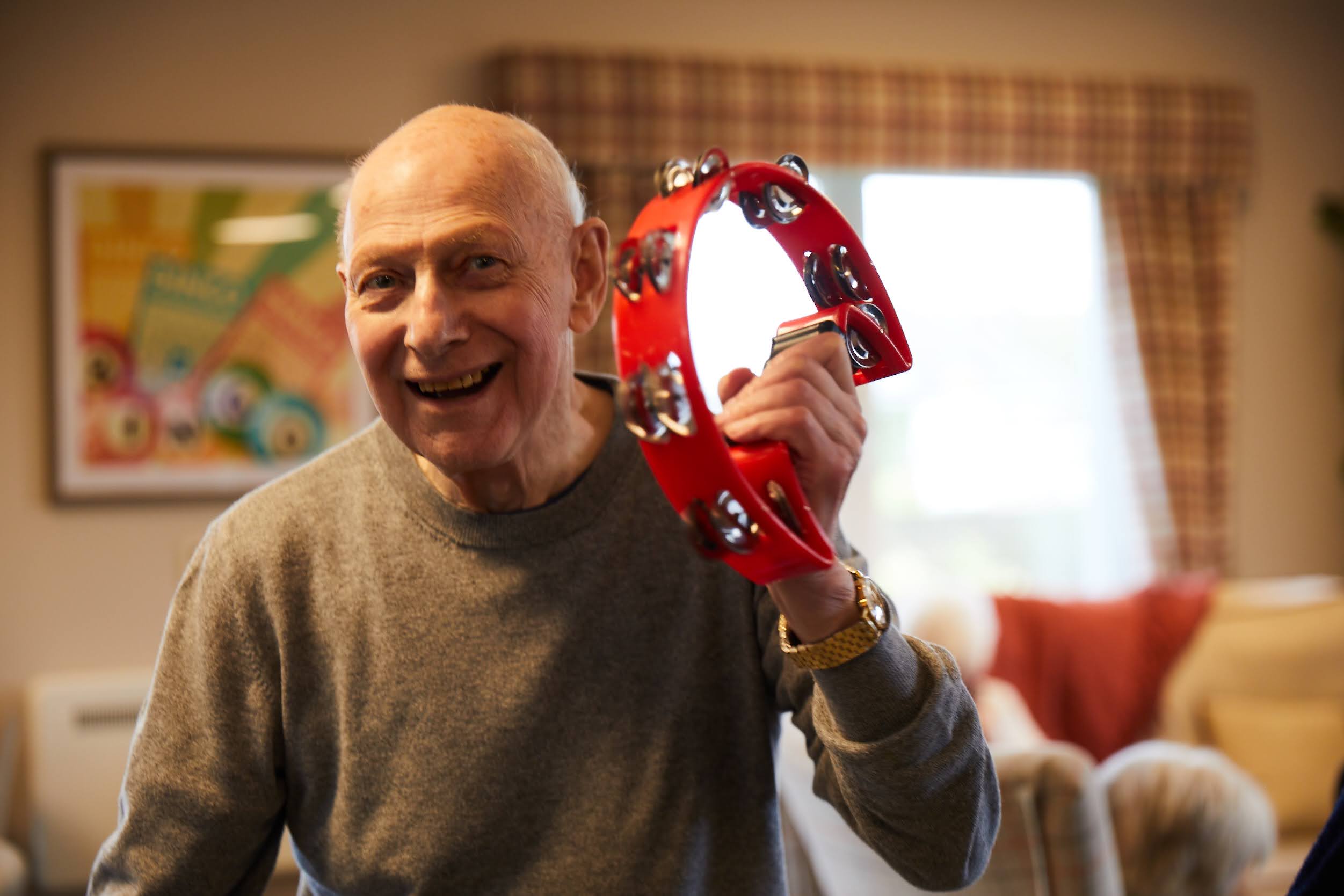 A man playing a tamborine in the lounge at Brampton Lodge Day Centre