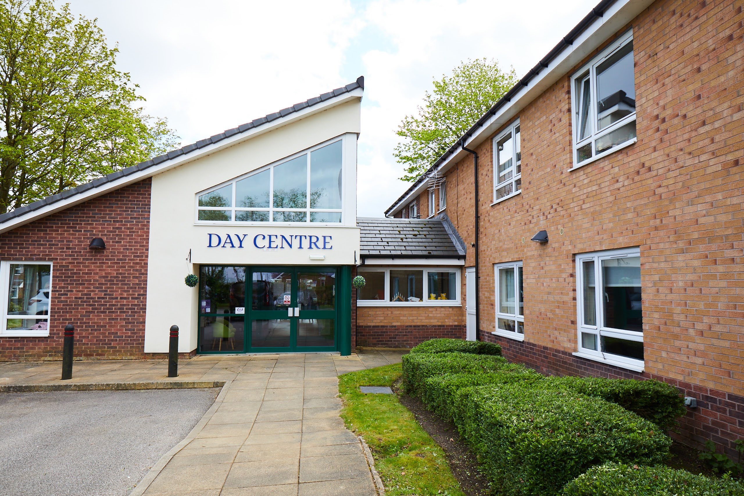 Path leading to building angles roof and Day Centre sign.