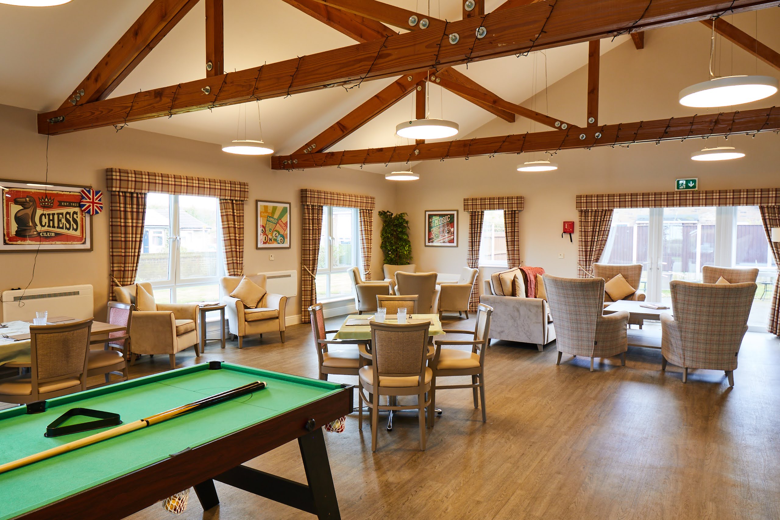 Wide view of Brampton Lodge Day Centre lounge with he pool table, tables and chairs, sofas and arm chairs