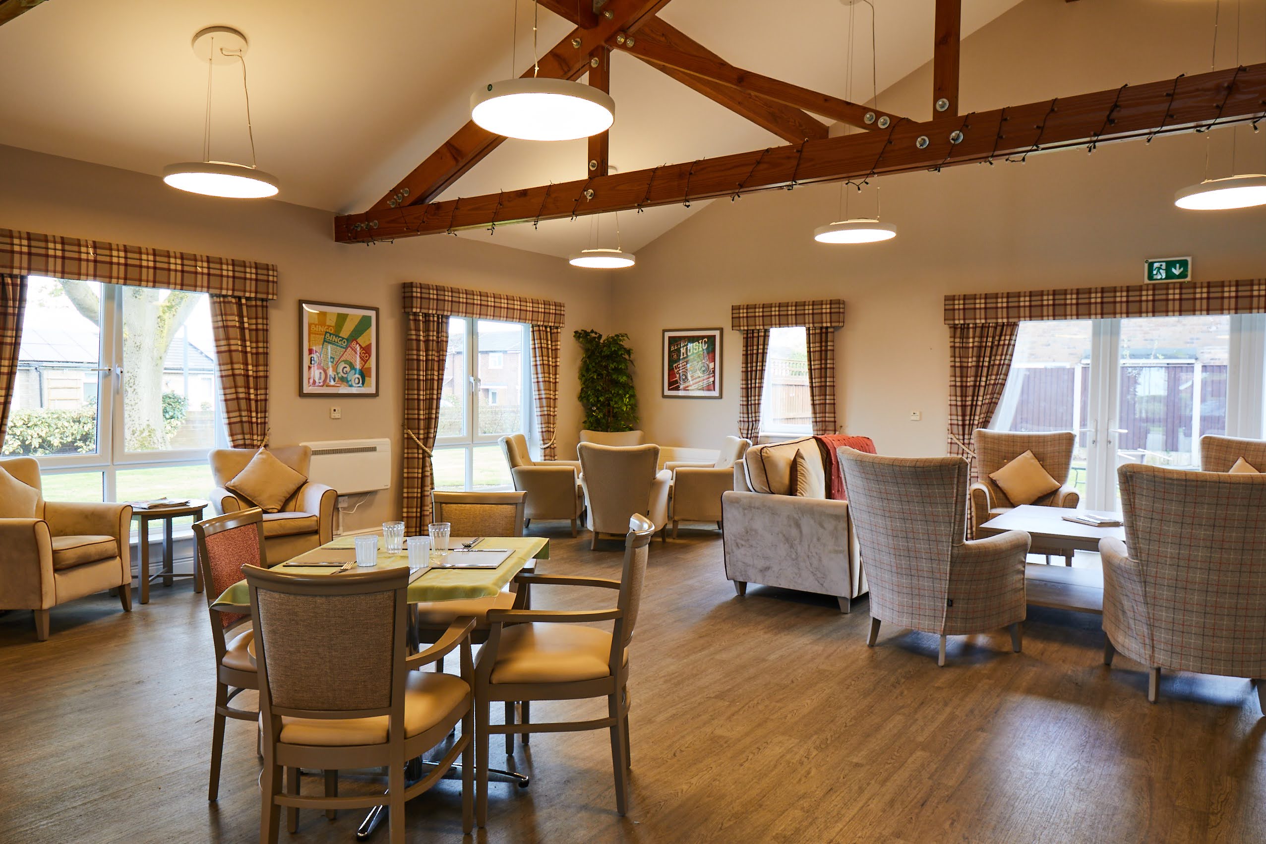 Tables, chairs, cosy arm chairs and sofas in the airy Brampton Lodge Day Centre lounge.