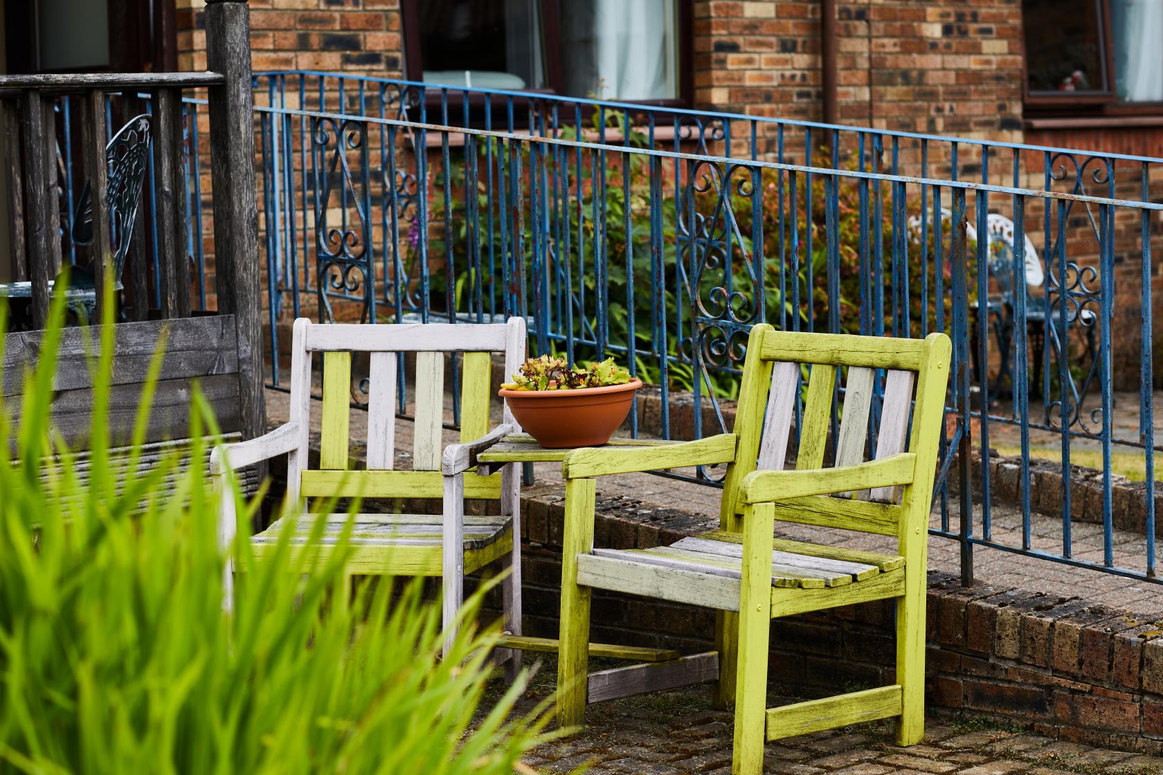 Yellow, wooden garden seats with table in between at Spiers Care Home