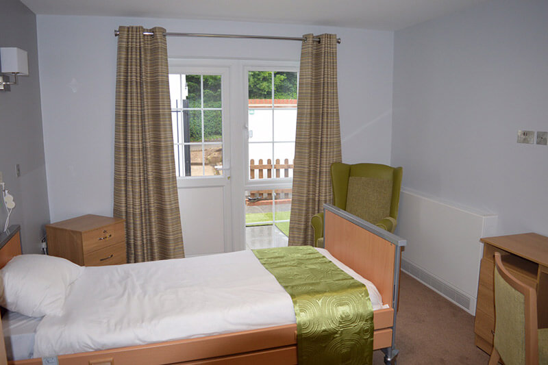 A ground floor bedroom at Berehill with glass door leading to a patio outside.
