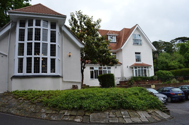 Large white building with red roof and a section with ground floor to roof windows.