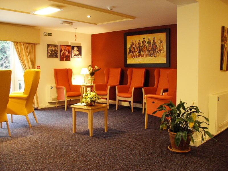 Cosy, red armchairs in the lounge at Marlborough House Care Home.