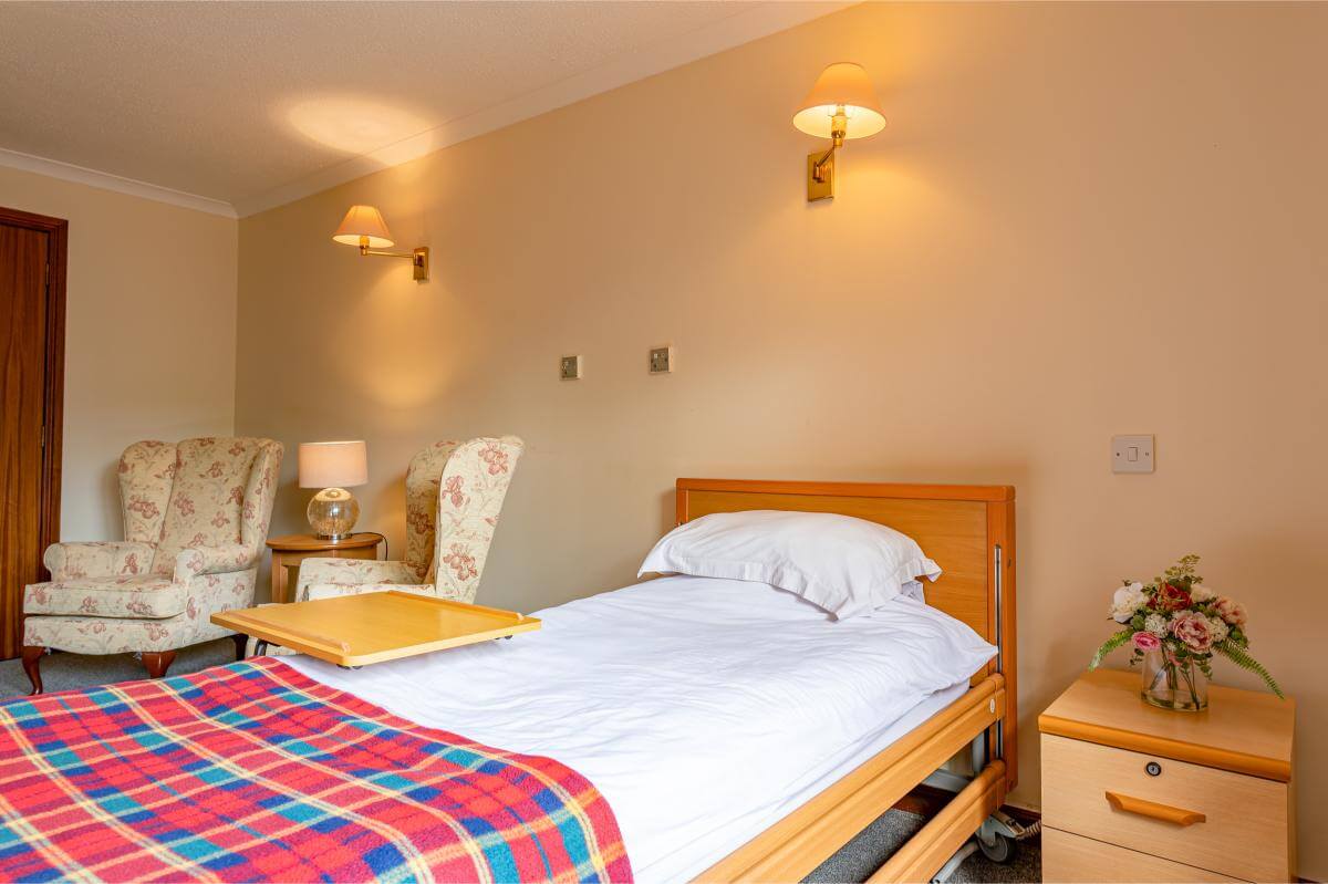 View of the bed with a tartan throw at Spiers Care Home.