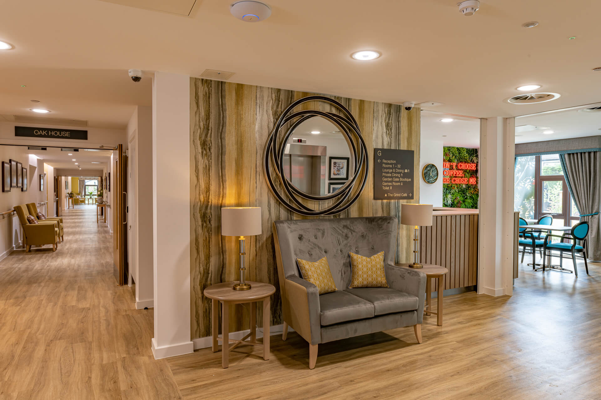 Sofa under mounted, circular wall mirror in the entrance at Surbitonain