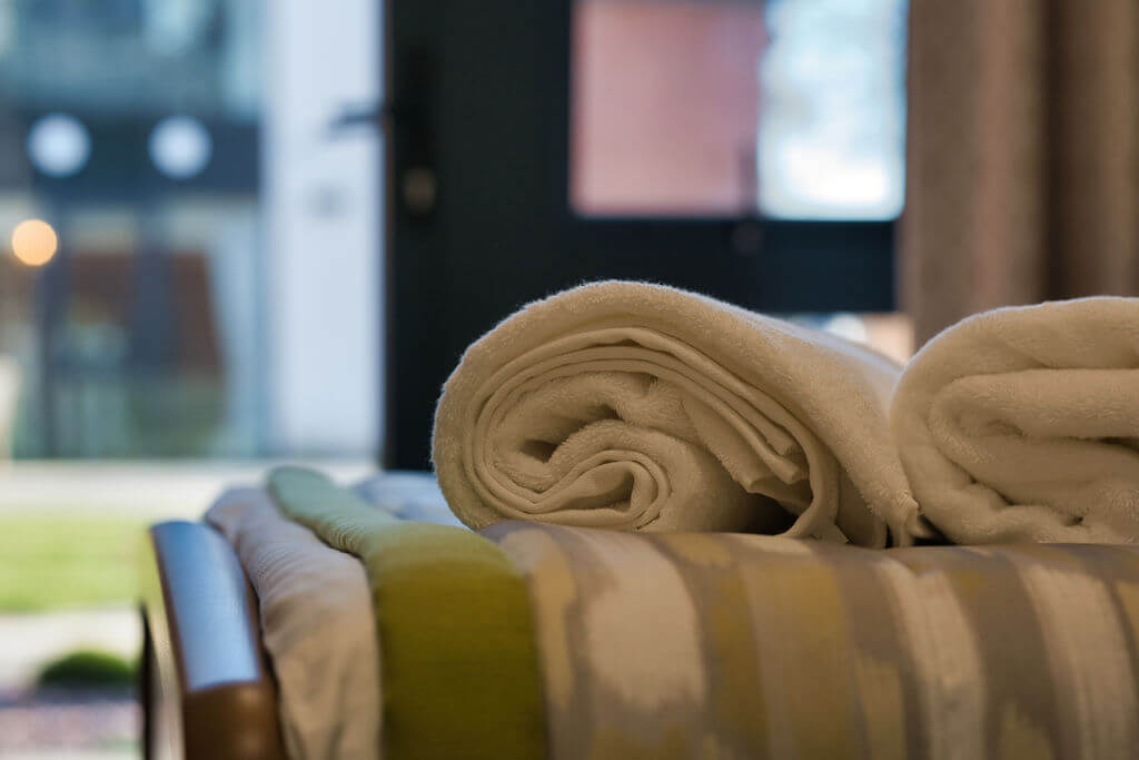 Close up of rolled up white towel on a bed