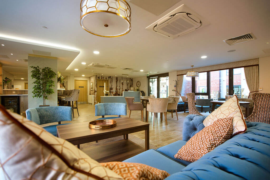 blue sofas and cushiosn with tables and arm chairs in a room.