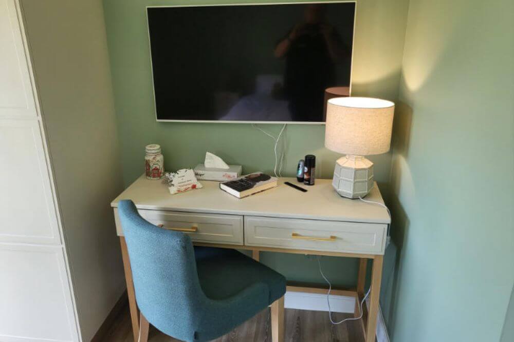 bedroom desk with comfortable fabric chair and TV