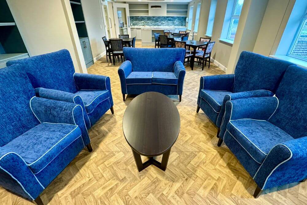 Royal blue fabric arm chairs surrounding an oval, wooden coffee table