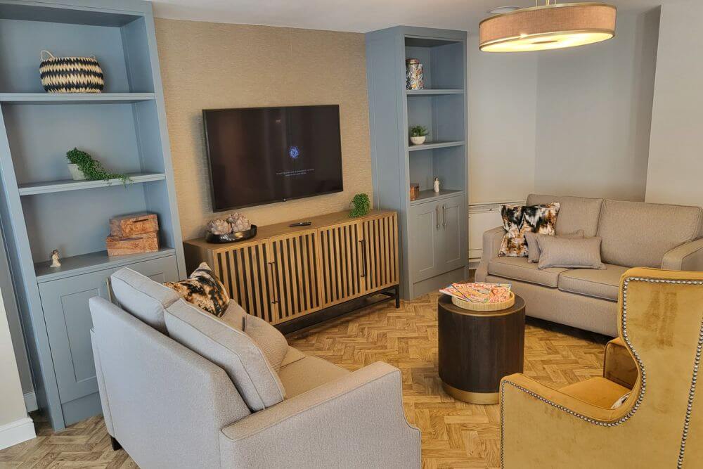 Room with mounted TV and light grey sofas opposite one another with a coffee table in the middle.