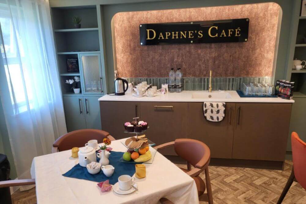 Table with tea cups, biscuits, cakes and fruit.
