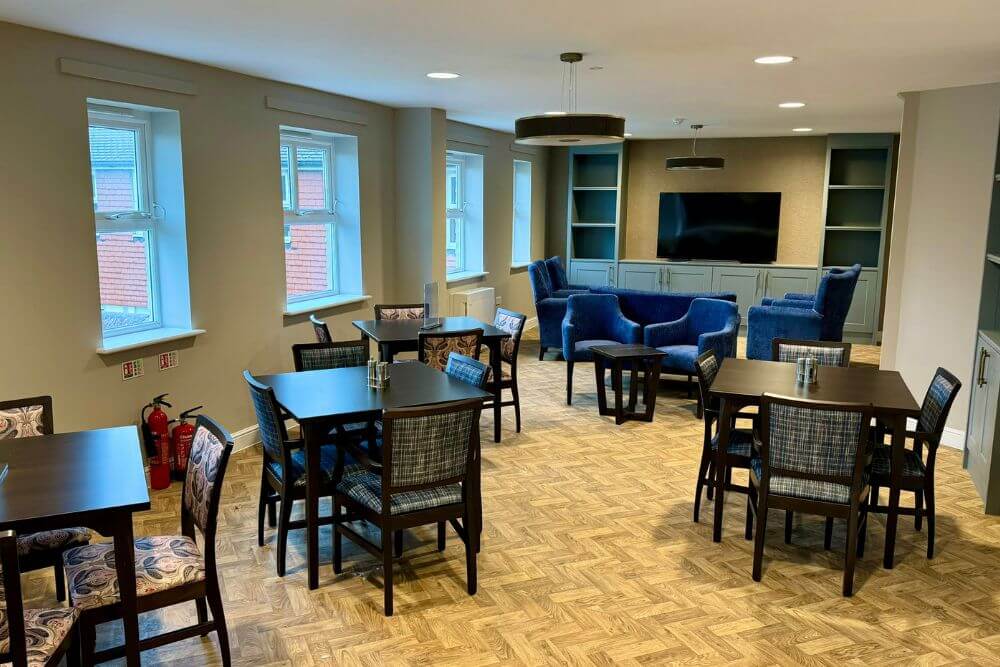 Square dining tables with blue sofas at the end of the room for lounging.